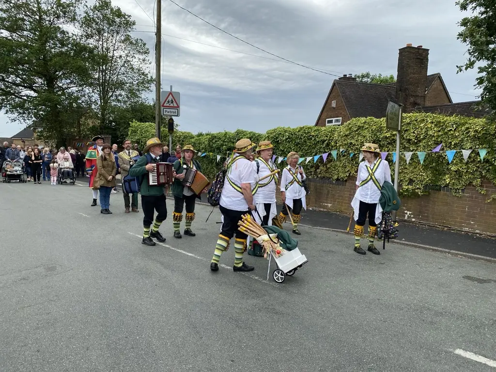 Leek Morris musicians and dancers walking down a country lane in costume
